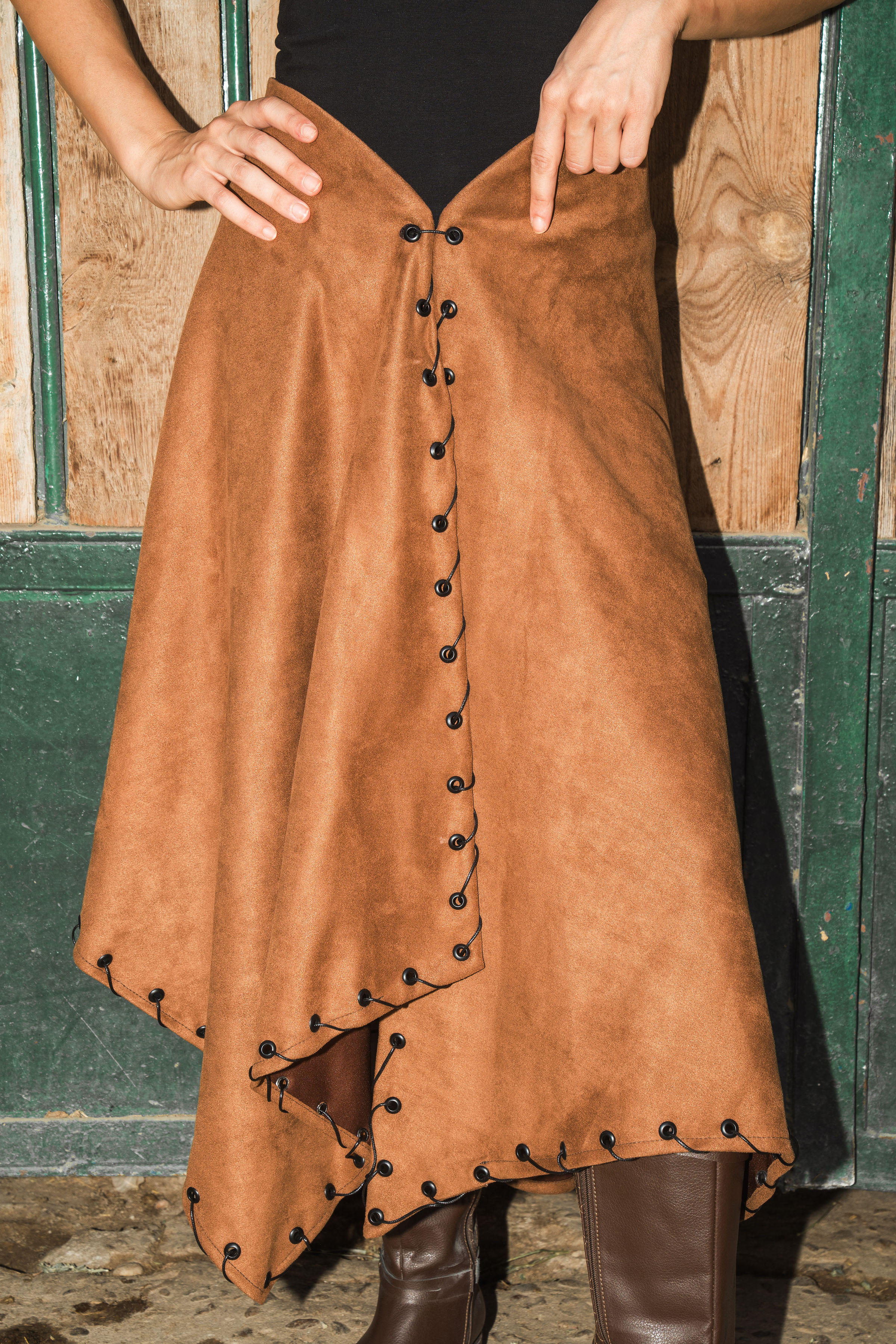 Brown suede skirt with black button details worn by a person against a wooden background