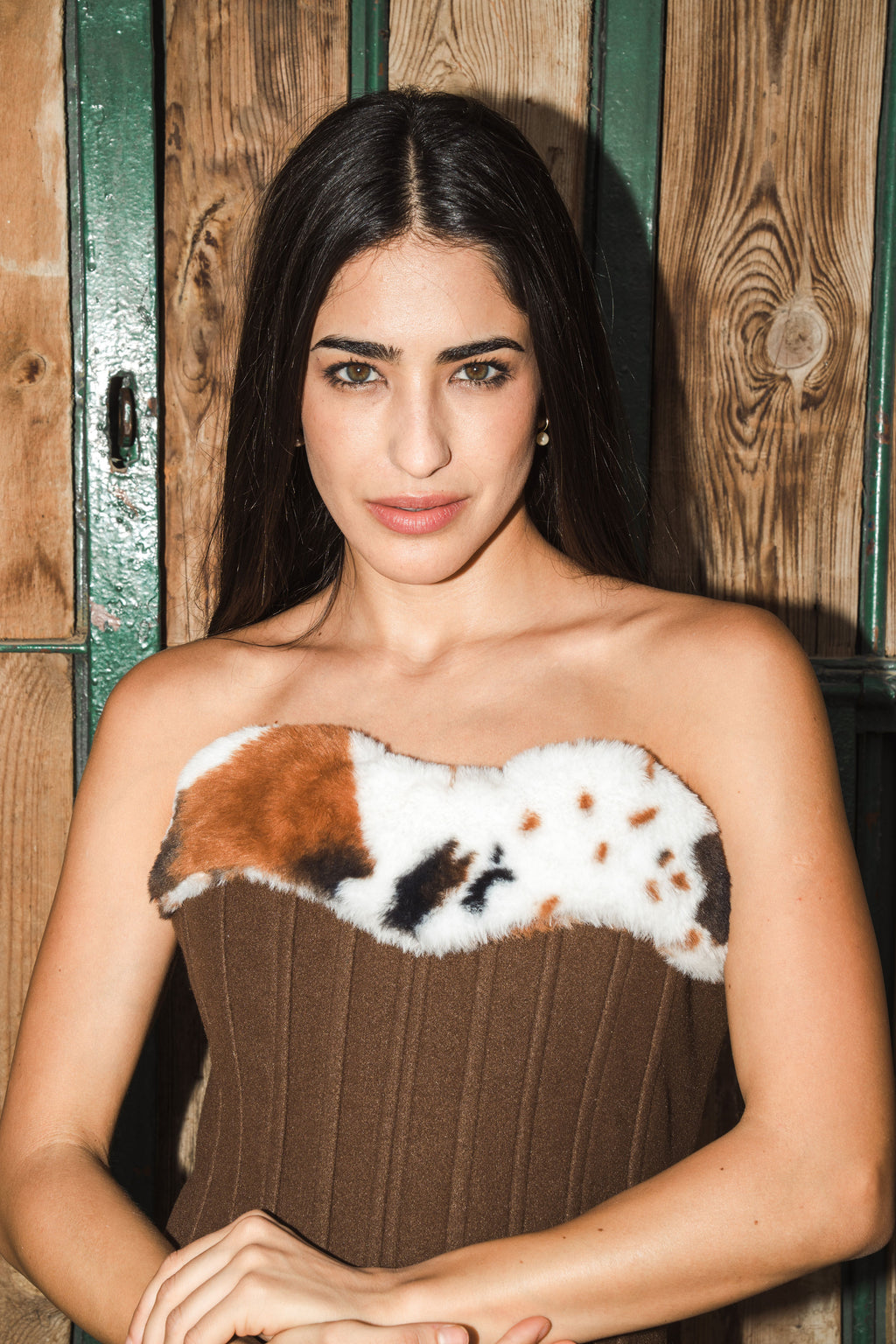 Woman wearing a strapless corset with a fur-like design against a wooden background