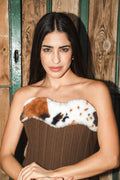 Woman wearing a strapless corset with a fur-like design against a wooden background