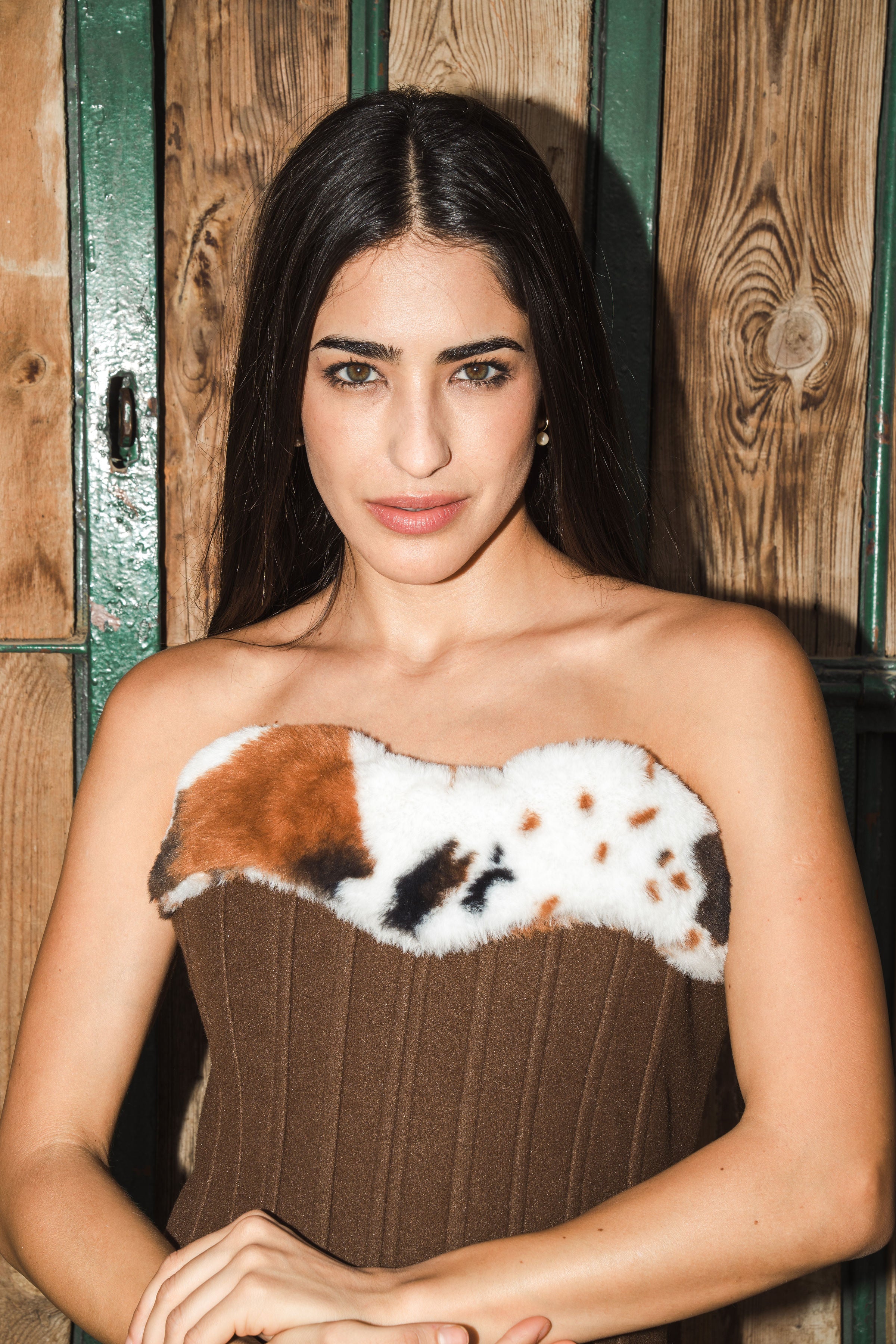 Woman wearing a strapless corset with a fur-like design against a wooden background